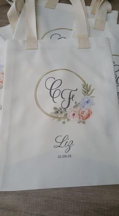 three white bags with floral designs on them sitting on a wooden table next to each other