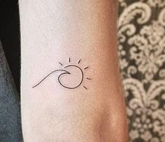 a woman's arm with a small sun and wave tattoo on the left wrist