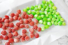 green and red candies sitting on top of white paper