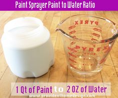 a measuring cup next to a plastic container on a wooden floor with the words paint sprayer paint to water ratio