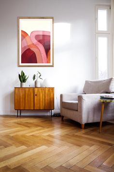 a living room filled with furniture and a painting hanging on the wall over a wooden floor