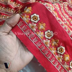 a hand holding a red cloth with flowers on it