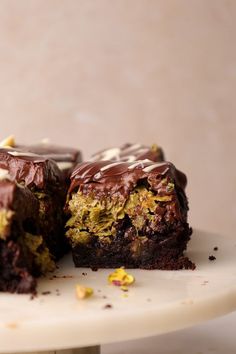 two pieces of cake sitting on top of a white plate with chocolate frosting and sprinkles