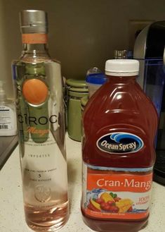 two bottles of liquid sitting on top of a counter next to a bottle of orange juice