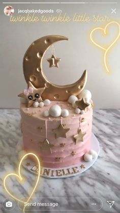 there is a pink cake with stars and a moon on it