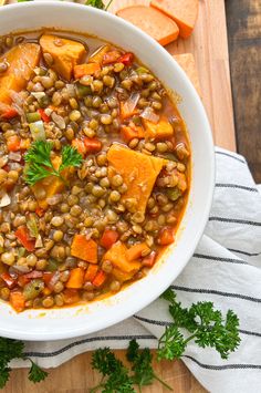 a white bowl filled with lentula and carrots on top of a wooden cutting board