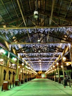 the inside of an indoor shopping mall with lots of lights hanging from it's ceiling