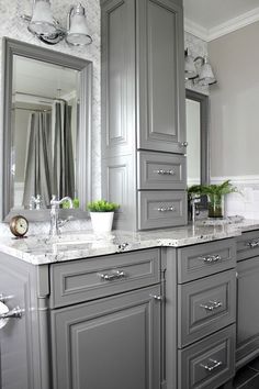 a bathroom with gray cabinets and marble counter tops