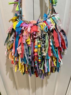 a multicolored handbag hanging on the front door with ribbons all over it