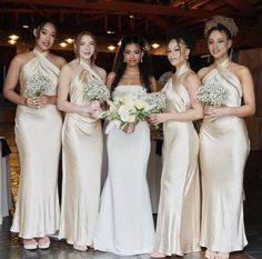 a group of women standing next to each other wearing dresses and holding bouquets in their hands