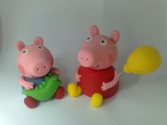 two peppa pig figurines sitting next to each other on a white surface