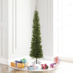 a small christmas tree in the corner of a room with presents on the floor next to it