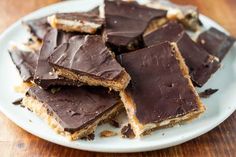 a plate full of pieces of chocolate peanut butter bars on top of a wooden table