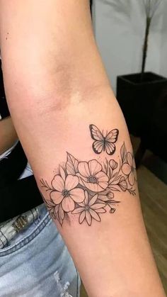 a woman's arm with a butterfly and flowers tattoo on the left side of her arm