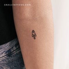 a small tattoo on the arm of a man with a rocket ship in it's center