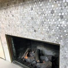 a fireplace that has some kind of mosaic tile on the wall above it and firewood in front of it