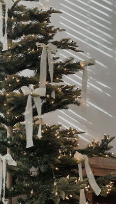 a christmas tree is decorated with white ribbon and lights