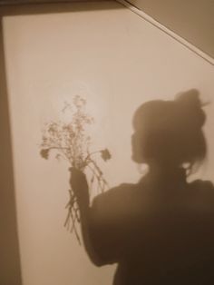 the shadow of a woman holding flowers in her hand