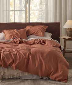 a bed with an orange comforter and pillows