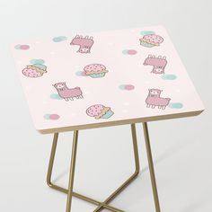 a small table with pink and blue llamas printed on the top, along with gold legs