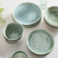 a table topped with plates and bowls filled with green food dyed dishes next to vases