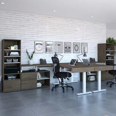 an office with two desks and chairs in front of a white brick wall that has pictures on it