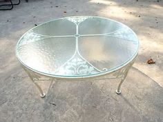 a glass table sitting on top of a cement ground