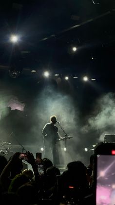 a man standing on top of a stage holding a microphone in front of a crowd