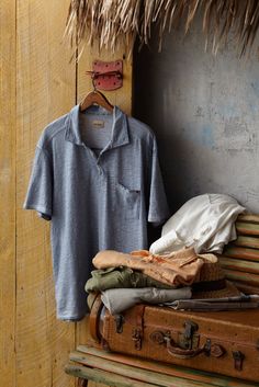 an old suitcase with clothes hanging on it and a t - shirt next to it