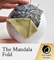 the hand is holding an origami ball with needles in it and thread on top