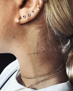 a woman with ear piercings on her neck and behind the ear is a chain