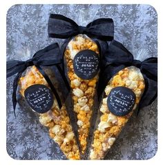 three bags filled with popcorn sitting on top of a table next to black ribbon bows