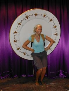 a woman standing in front of a purple curtain with a plate on her back and stars painted on it