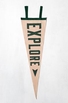 a sign that says explore hanging on a wall in front of a white wall with an arrow pointing to the right