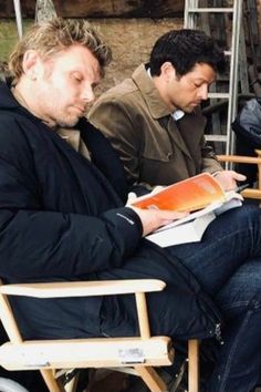 two men sitting in chairs looking at papers