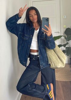 a woman taking a selfie with her cell phone in the air while wearing blue jeans