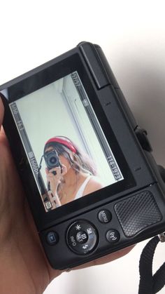 a hand holding a camera with a woman's face on the screen