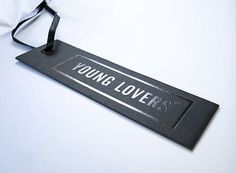 a young lover's sign hanging from a black ribbon on a white table top