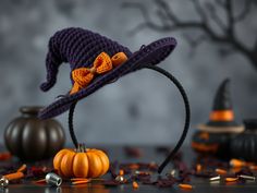 a purple crocheted hat with an orange bow sits on top of pumpkins