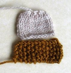 two crocheted hats sitting next to each other on top of a white surface