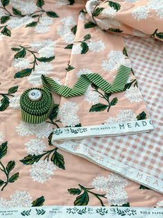 a close up of a table cloth with flowers on it and two measuring spoons