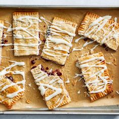 several desserts with icing and cranberries are on a baking sheet, ready to be eaten