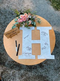 a wooden table topped with flowers and writing on it's sides next to a pen