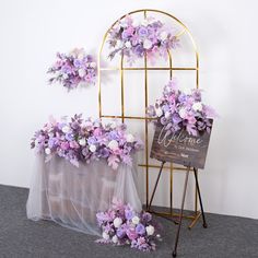 purple and white flowers are on display in front of a metal frame with a welcome sign