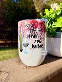 a wine glass sitting on top of a wooden table next to a potted plant