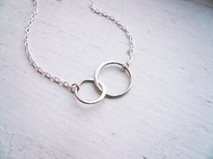 Small Entwined Rings Necklace in Sterling Silver - Sweet GiftSterling silver rings are entwined in an eternal bond.Two linked circles are partially flattened to catch the light and are suspended from two lengths of dainty sterling silver chain. One smaller and one larger circle can signify your special relationship, whether it be sisters, partners, or mother and child. Circles measure about 3/4" long and nearly 1/2" tall overall. Finished with a sterling silver spring ring clasp. This necklace m White Gold Circular Jewelry For Weddings, Delicate Circular Wedding Jewelry, Infinity Shaped Simple Wedding Jewelry, Rings Necklace, Silver Spring, Mother And Child, Mother Day Gifts, Ring Necklace, Spring Rings