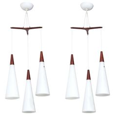 four glass and wood wind chimes hanging from the ceiling with white balls on top