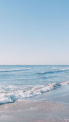 an ocean view with waves coming in to shore and the sky above it is clear