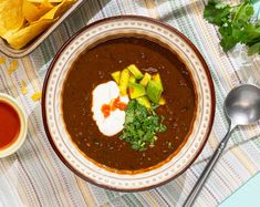 a bowl of black bean soup with avocado, sour cream and cilantro