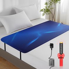 a bed with an electric blanket and pillow on it, next to a battery plugged in